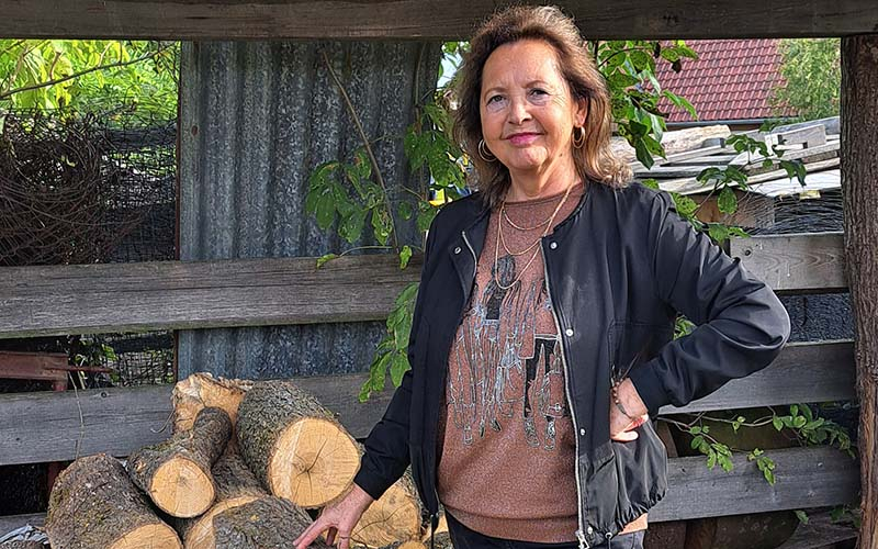 Die Autorin vor geschichtetem Holz im Freilichtmuseum