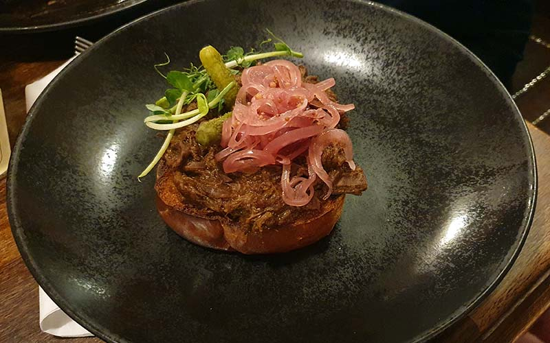 Geschnetzelte Rindfleisch auf geröstetem Milchbrot mit Cornichons, Gurkerl und marinierten Zwiebel