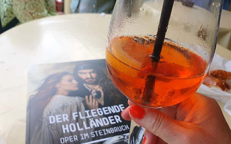 Ein Gläschen Aperol, eine Bretze und im Programm schmökern